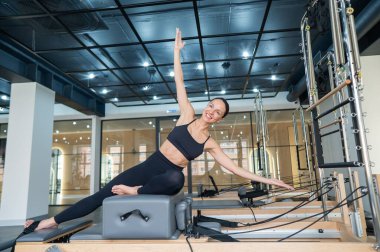 Kafkasyalı kadın yenilikçi makinede yan büküş yapıyor.