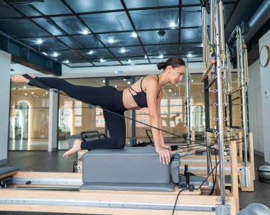 Kafkas kadın yenilikçi makine üzerinde bacak egzersizi yapıyor.