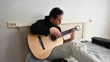 Genç adam akustik gitar çalıyor. Parmak Biçimi