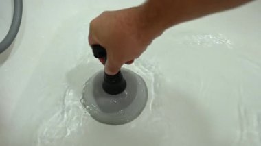 Adamın biri lavabosundaki tıkanıklığı pompayla temizliyor.
