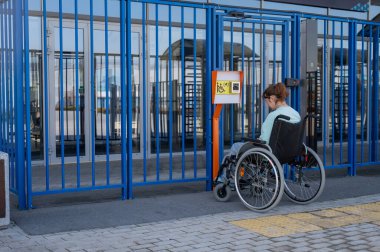 Tekerlekli sandalyedeki bir kadın engelliler için çağrı düğmesi kullanır.