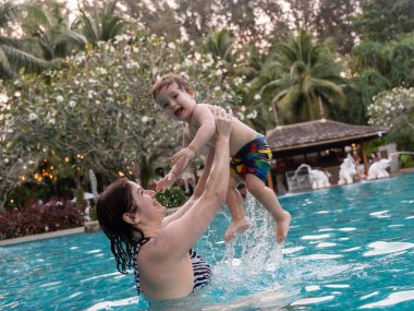 Beyaz kadın tatilde havuzda yüzerken oğlunu kucağına aldı