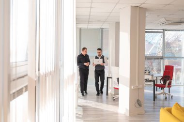 İki beyaz adam dizüstü bilgisayara bakıyor ve iş tartışıyorlar.