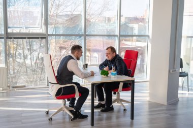 İki beyaz adam bir iş toplantısında iletişim kuruyor.