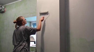 Kafkas kadın silindirle duvar boyuyor.