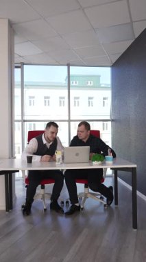 İki beyaz adam bir masada oturup iş tartışıyorlar.