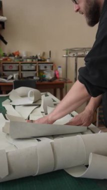 Beyaz sakallı adam bir atölyede bronzlaştırıcı olarak çalışıyor.