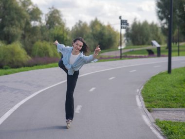 Beyaz kadın parkta paten kayıyor.