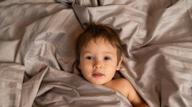 Beyaz tenli şirin bir çocuğun yatakta yatışının üst görüntüsü.