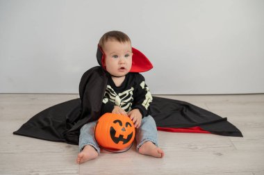 Beyaz arka planda şeker sepeti tutan Dracula Cadılar Bayramı kostümlü beyaz tatlı çocuk.