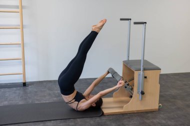Beyaz kadın klasik sandalyede pilates yapıyor.