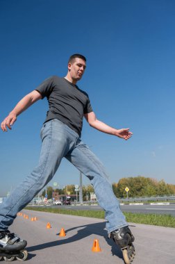 Beyaz bir adam slalom pistinde paten kayıyor.