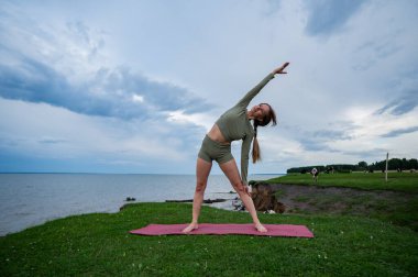 Beyaz kadın nehir kıyısında yoga yapıyor.