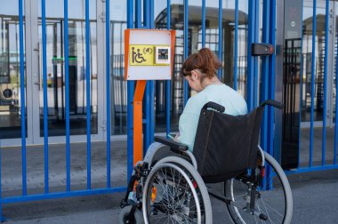 Tekerlekli sandalyedeki bir kadın engelliler için çağrı düğmesi kullanır.