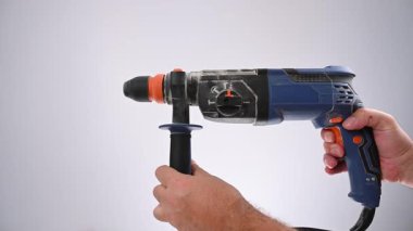 Bir adam matkabı çalıştırır. Sesli video