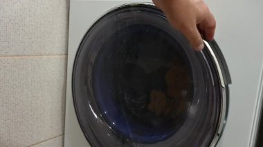 Bir adam çamaşır makinesinden çamaşır boşaltıyor. Sesli video
