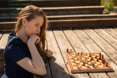 Beyaz kadın dışarıda satranç oynuyor.