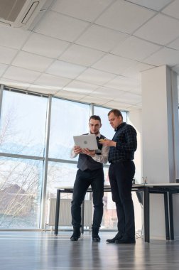 İki beyaz adam dizüstü bilgisayara bakıyor ve iş tartışıyorlar.