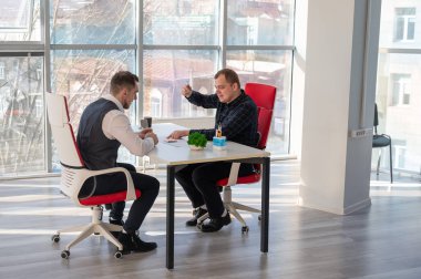 İki beyaz adam bir iş toplantısında iletişim kuruyor.