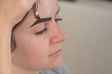 Beyaz kadın kaş boyama prosedürü uyguluyor.