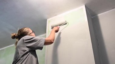 Kafkas kadın silindirle duvar boyuyor.