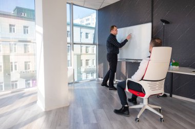 Beyaz bir kurulda iş tartışan iki beyaz adam.