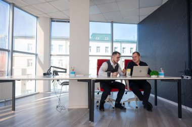 İki beyaz adam bir masada oturup iş tartışıyorlar.