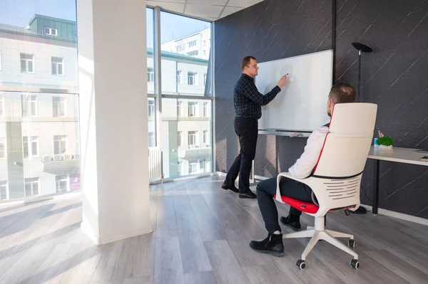 Beyaz bir kurulda iş tartışan iki beyaz adam.