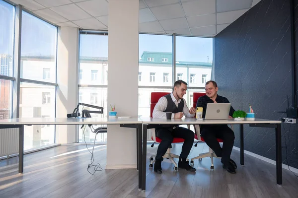 İki beyaz adam bir masada oturup iş tartışıyorlar.