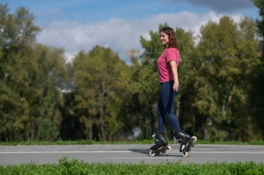 Beyaz kadın parkta paten kayıyor.