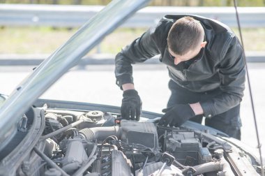 Bir adam arabasındaki bujileri değiştirir.