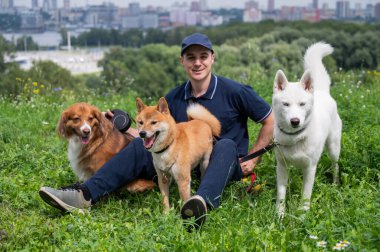 Beyaz bir adam üç köpekle yürür. Köpek gezdirici