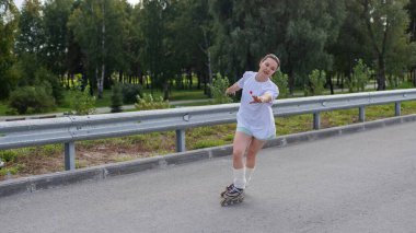 Beyaz kadın yolda hızla paten kayıyor.