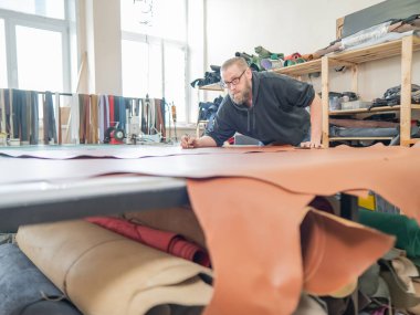 Beyaz sakallı adam bir atölyede bronzlaştırıcı olarak çalışıyor.