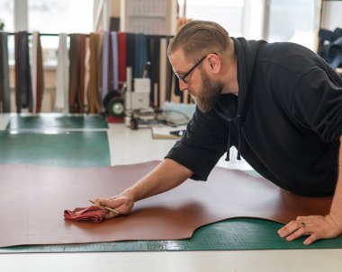 Beyaz sakallı adam bir atölyede bronzlaştırıcı olarak çalışıyor.