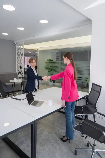 Beyaz erkek ve kadın ofiste selamlaşıp el sıkışıyor.