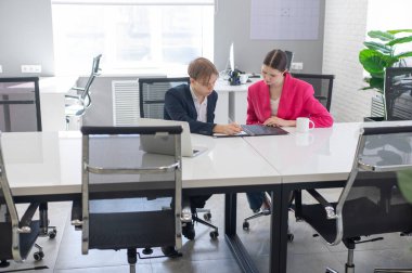 Kadın ve erkek ofiste otururken konuşuyorlar.