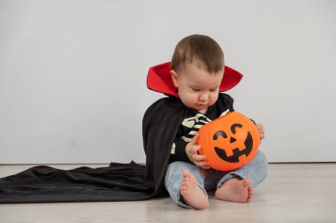 Beyaz arka planda şeker sepeti tutan Dracula Cadılar Bayramı kostümlü beyaz tatlı çocuk.