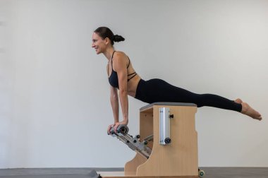 Beyaz kadın klasik sandalyede pilates yapıyor.