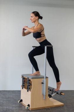 Beyaz kadın klasik sandalyede pilates yapıyor.