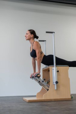 Beyaz kadın klasik sandalyede pilates yapıyor.