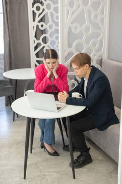 Meslektaşlar dizüstü bilgisayarda oturup iş konuşuyorlar.