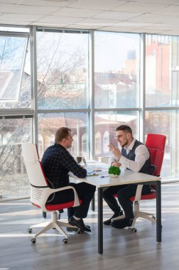 İki beyaz adam bir iş toplantısında iletişim kuruyor.