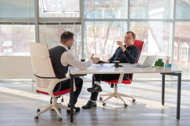 Bir ofiste pazarlık yapan iki beyaz adam.