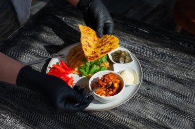 Siyah eldiven giyen bir şef fajita hazırlar.