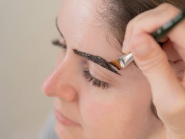 Beyaz kadın kaş boyama prosedürü uyguluyor.