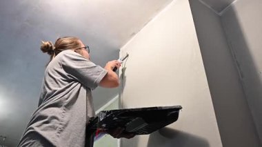 Kafkas kadın silindirle duvar boyuyor.