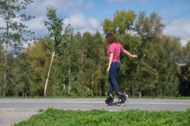 Beyaz kadın parkta paten kayıyor.