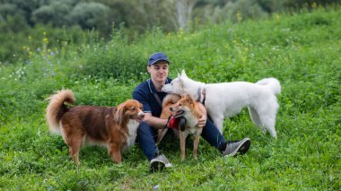 Beyaz bir adam üç köpekle yürür. Köpek gezdirici