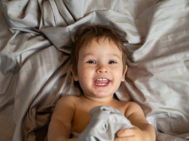 Beyaz tenli şirin bir çocuğun yatakta yatışının üst görüntüsü.